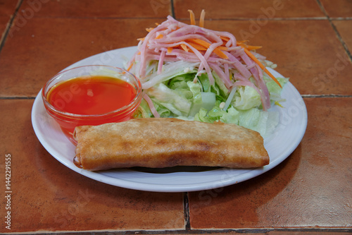 Obraz na płótnie A plate of food with a piece of fried food and a salad. The salad has carrots and ham w salonie