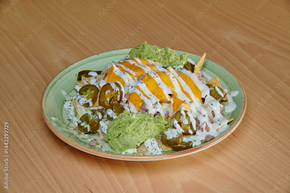 A plate of food with a green sauce on top of it. The sauce is made of avocado and cheese. The plate is on a wooden table