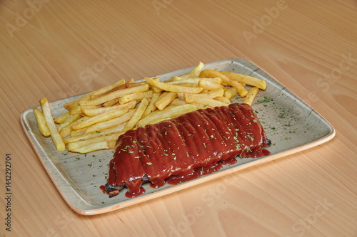 Obraz na płótnie A plate of ribs and french fries. The fries are cut into strips and are covered in sauce w salonie