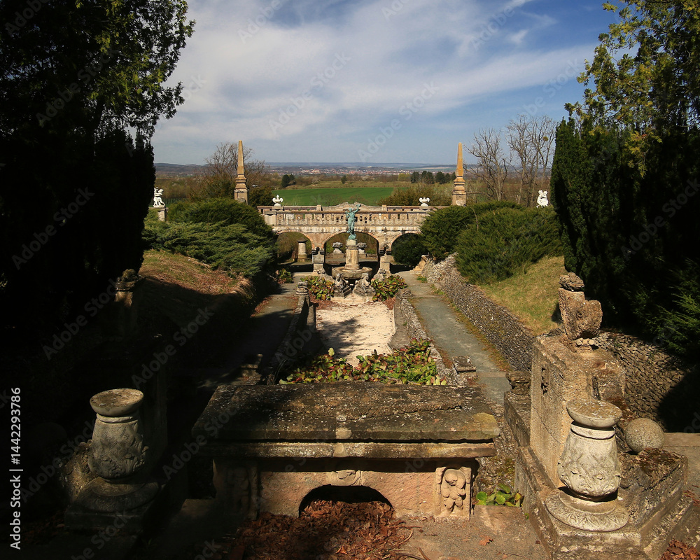 Fountain garden terrace of Roseburg in Germany with stone sculptures and trimmed hedges under a clear spring sky