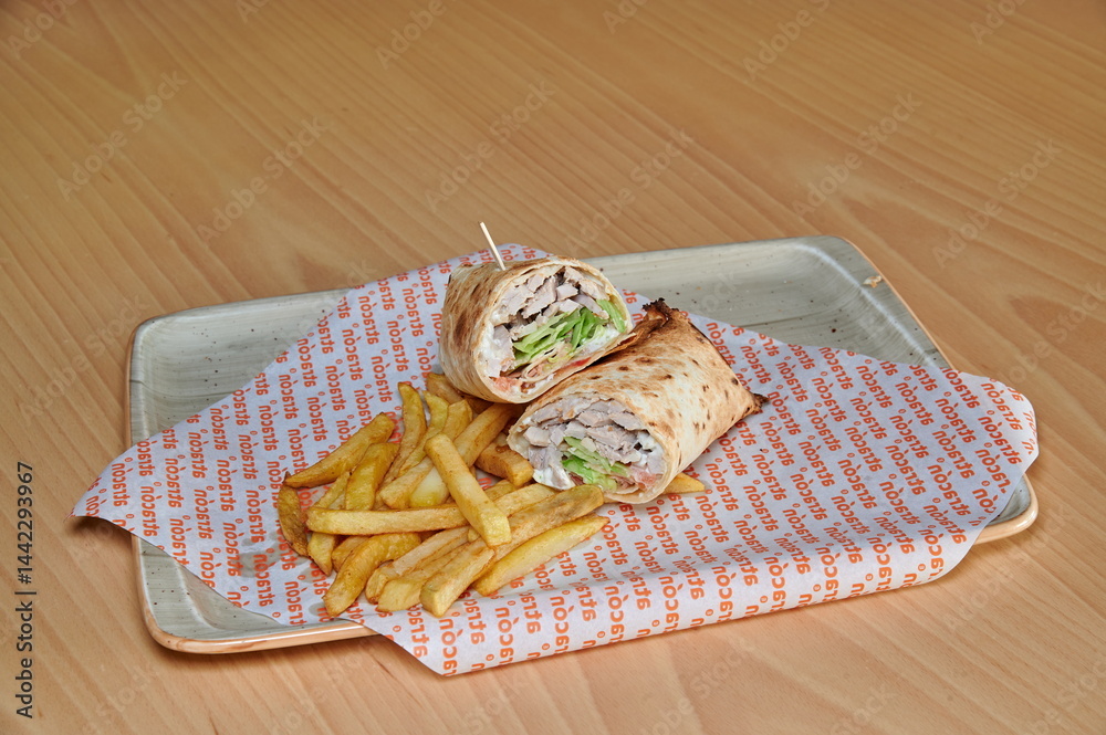 A sandwich and french fries are on a plate. The sandwich is cut in half and the fries are cut into small pieces