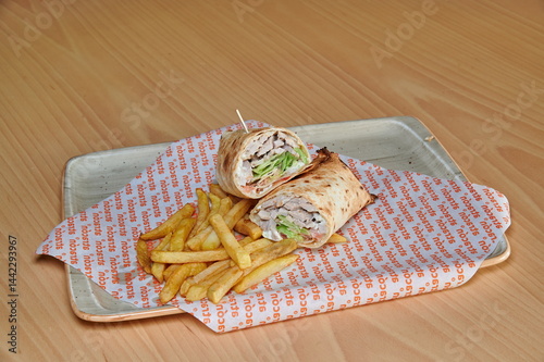 Obraz na płótnie A sandwich and french fries are on a plate. The sandwich is cut in half and the fries are cut into small pieces w salonie
