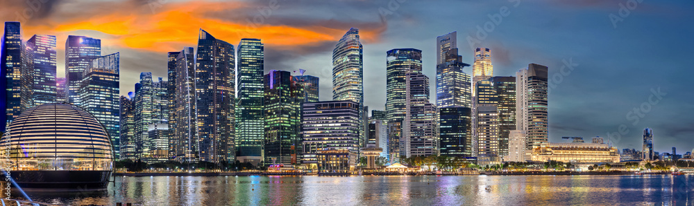 Fototapeta premium Singapore CBD City Skyline on the river at Sunset with vibrant colours of the high-rise apartment and office towers with the beautiful colours of the sky. Panorama view of Singapore CBD buildings 