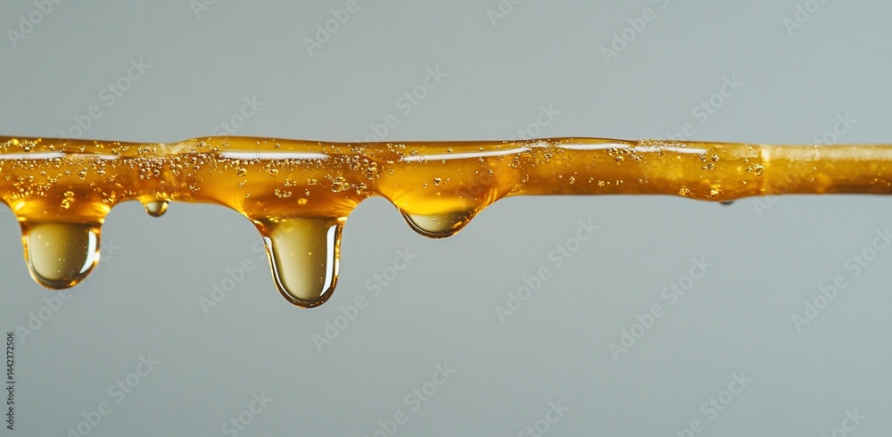 Golden liquid dripping from a stick, close-up view.