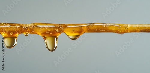 Obraz na płótnie Golden liquid dripping from a stick, close-up view. w salonie
