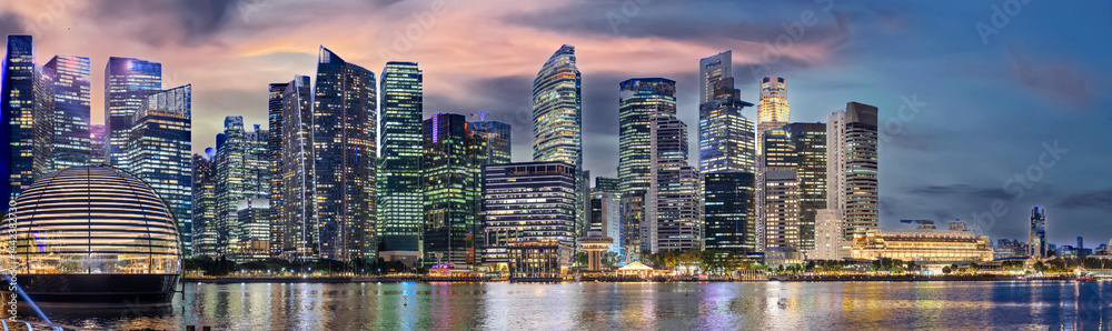 Naklejka premium Singapore CBD City Skyline on the river at Sunset with vibrant colours of the high-rise apartment and office towers with the beautiful colours of the sky. Panorama view of Singapore CBD buildings 