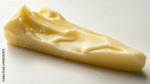 Close-up of a wedge of creamy, pale yellow cheese on a white background.
