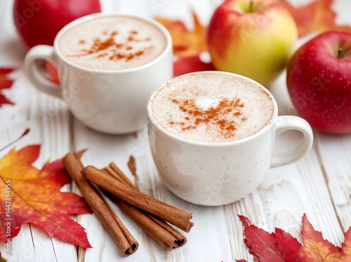 Obraz na płótnie Two mugs of spiced apple cappuccino with cinnamon sticks and autumn leaves on white wooden table. w salonie