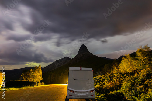 A motorhome parked under the stunning Northern Lights in Lofoten Islands, Norway, with colorful auroras in the sky.