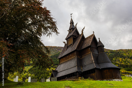Hopperstad Stavkyrkje in South Norway, a historic wooden church surrounded by autumn trees and a peaceful graveyard. photo