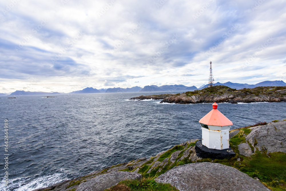 A scenic view of Henningsvær in Lofoten Islands, northern Norway, showcasing traditional buildings along the harbor with mountains in the background.