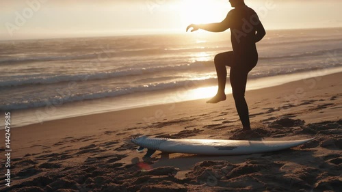 A surfer warming up on the beach at sunset, preparing to enter the ocean and ride the waves. Perfect for surfing, fitness, and travel videos.
