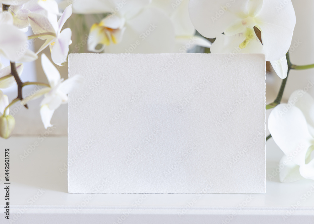 Card near white orchid flowers on table close up, pastel romantic wedding mockup