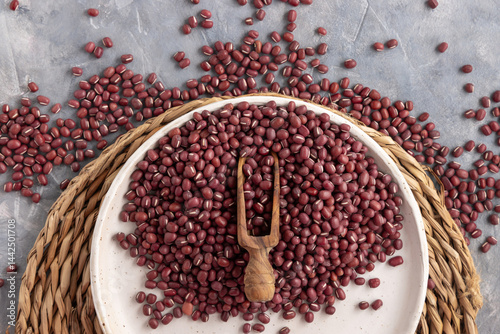 Obraz na płótnie Plate full of dried red azuki beans with a wooden scoop top view. East Asian legumes, vegetarian food w salonie