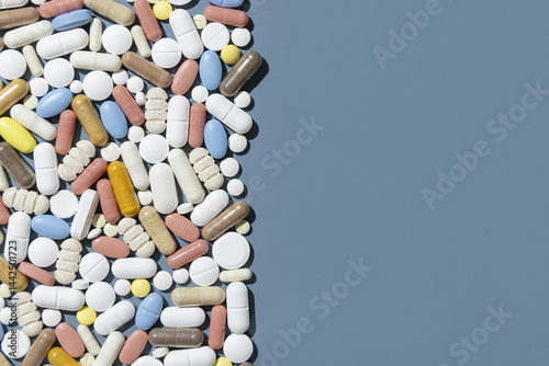 Obraz na płótnie Pile of mixed white, yellow and blue medical capsules and pills on blue top view, border w salonie