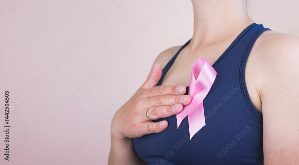Young woman holding pink ribbon on pink background with space for text.