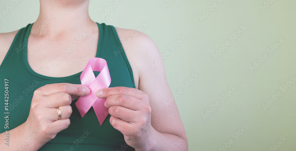Young woman holding pink ribbon on green background with space for text.