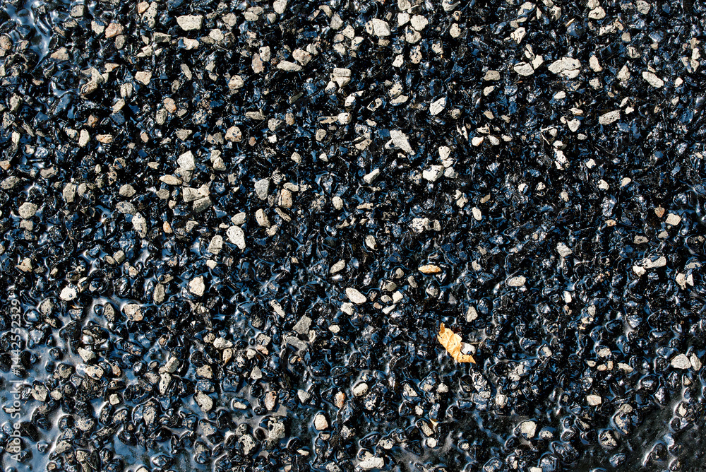 Road repair patching compound closeup. Driveway asphalt pothole patch. Compound filled potholes and cracks on an asphalt surface. Bitumen and gravel mix for repair asphalt road