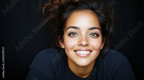 A woman with green eyes and a black shirt. She is smiling. She has a white smile