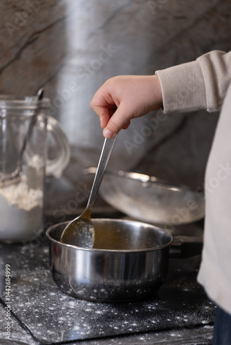 Canvastavla Child stirring melted ingredients in a saucepan on the stove vertical photo