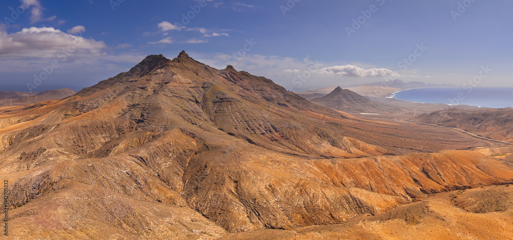 Naklejka premium Dramatic aerial panoramic image of Montana Cardon, the Jandia peninsular and the volcanic mountain landscape of Fuerteventura Canary Islands Spain