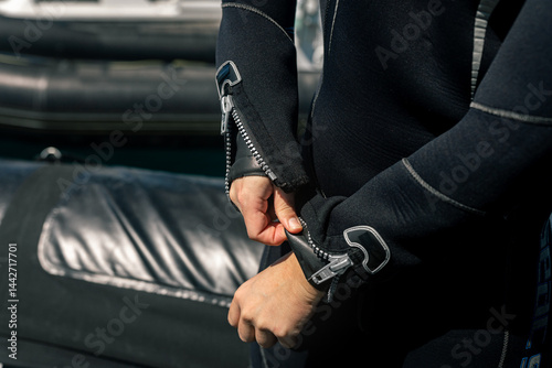 Fotografie Diver zipping up diving suit on boat before scuba diving