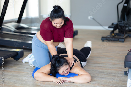 Obraz na płótnie Friends back massage. beautiful young chubby overweight woman wearing sporty fitness clothes doing exercise indoors at gym fitness sport club, body and health care w salonie