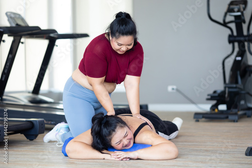 Obraz na płótnie Friends back massage. beautiful young chubby overweight woman wearing sporty fitness clothes doing exercise indoors at gym fitness sport club, body and health care w salonie