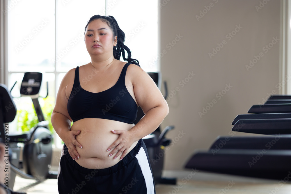 Portrait woman and fat belly. beautiful young chubby overweight woman wearing sporty fitness clothes doing exercise indoors at gym fitness sport club, body and health care