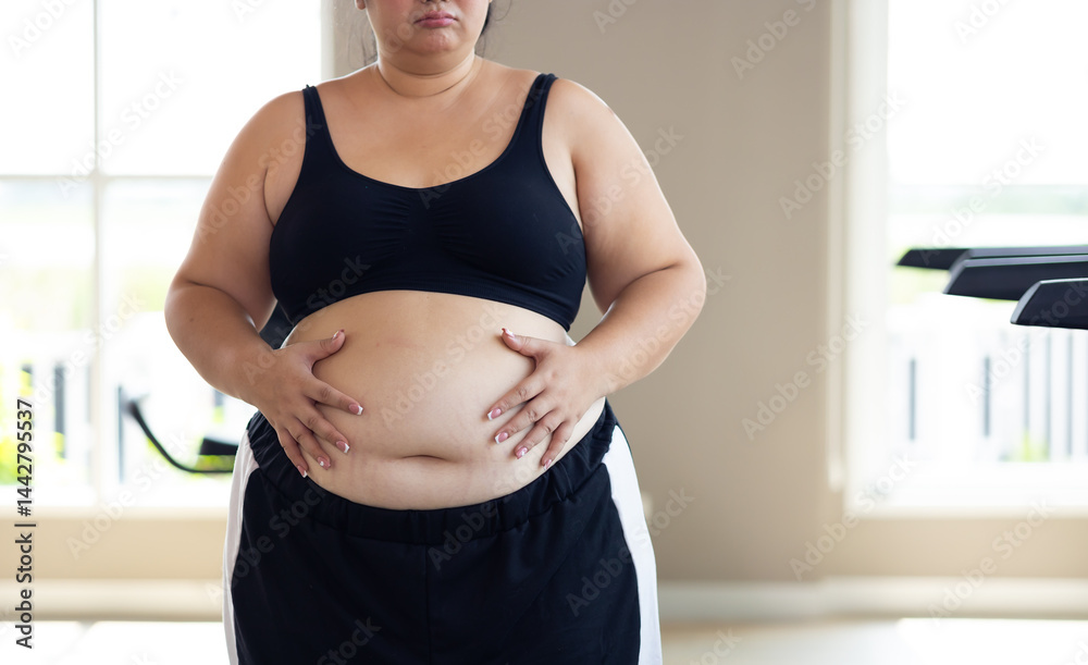 Portrait woman and fat belly. beautiful young chubby overweight woman wearing sporty fitness clothes doing exercise indoors at gym fitness sport club, body and health care