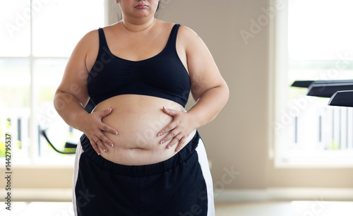Obraz na płótnie Portrait woman and fat belly. beautiful young chubby overweight woman wearing sporty fitness clothes doing exercise indoors at gym fitness sport club, body and health care w salonie