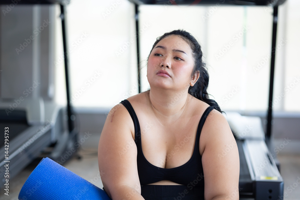 Tired fat asian woman. beautiful young chubby overweight woman wearing sporty fitness clothes doing exercise indoors at gym fitness sport club, body and health care