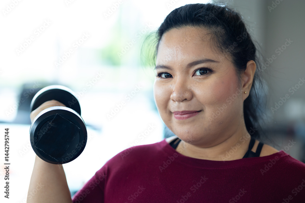 Young woman exercising with dumbbells. beautiful young chubby overweight woman wearing sporty fitness clothes doing exercise indoors at gym fitness sport club, body and health care