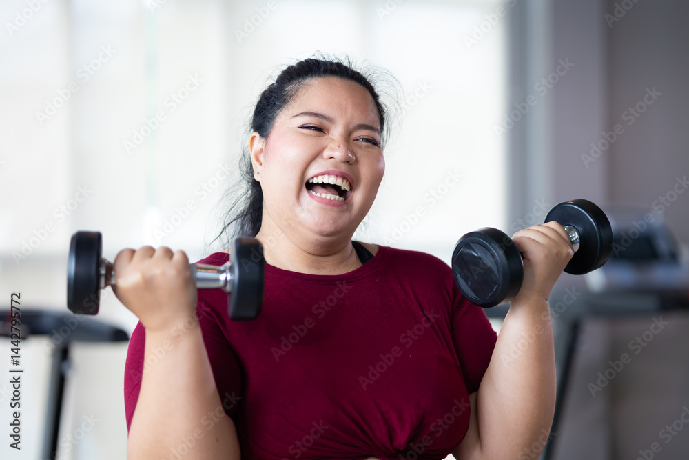 Young woman exercising with dumbbells. beautiful young chubby overweight woman wearing sporty fitness clothes doing exercise indoors at gym fitness sport club, body and health care