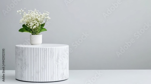 A small white vase with delicate flowers on a modern round marble side table, minimalist interior design, neutral color palette, and serene atmosphere.