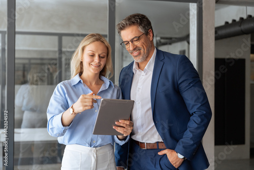 Two partners, colleagues, team of professional finance specialist business people working together. Mature mentor senior leader man, young woman manager discussing project sitting at desk in office
