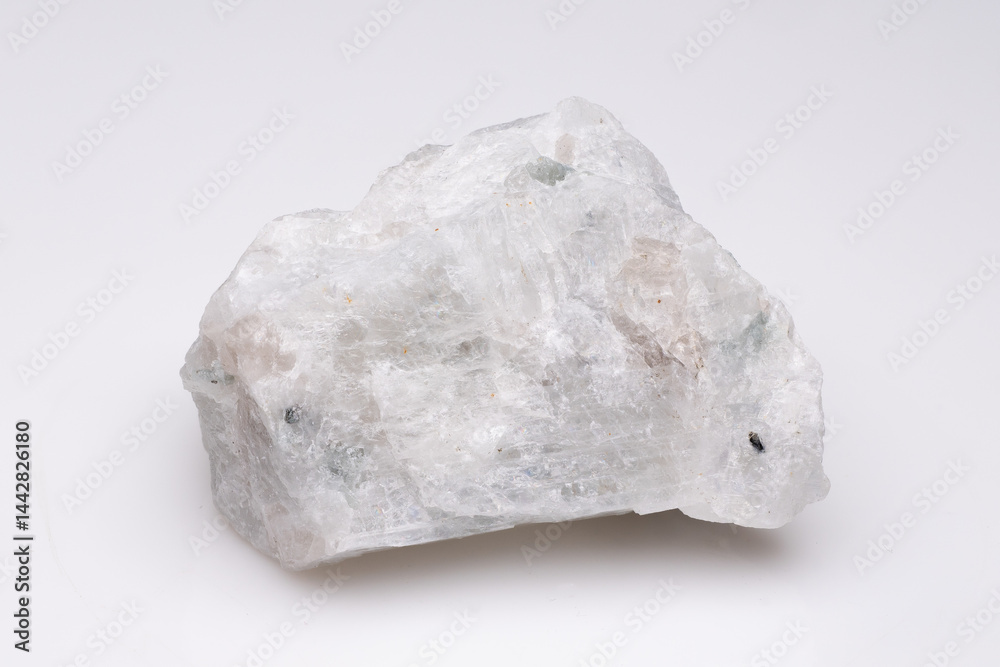 Close-up view of a rough, translucent mineral specimen with subtle green hues against a plain white background, showcasing its crystalline structure and natural texture