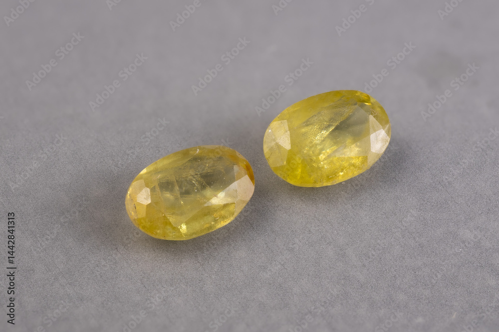 Pair of Natural Faceted Yellow Gemstones of Sphene on Gray Background