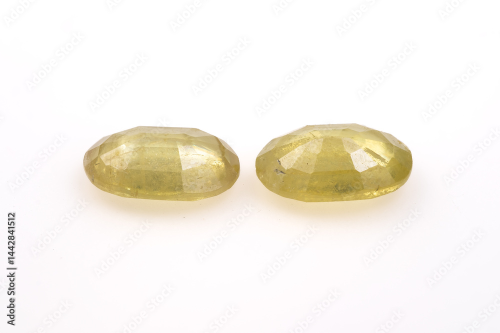 Pair of Faceted Yellow Green Natural Sphene Gemstones Faceted Oval Shape on White Background
