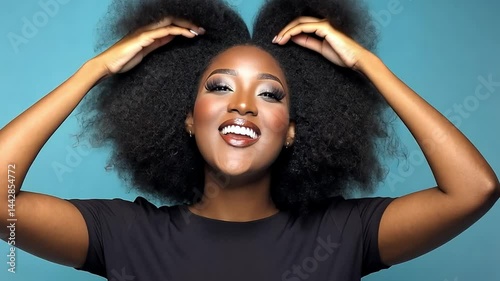 Joyful Young Woman with Natural Afro Hairstyle Smiling Brightly Against a Blue Background