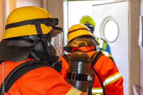 A firefighters in full protective gear, mask, and oxygen tank stands ready during a fire drill on board. Fully equipped, he executes fire suppression tasks with required precision.