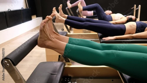 Women performing pilates footwork exercises on a reformer