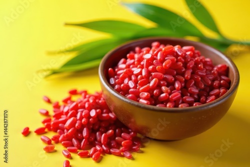 Bowl of uncooked red rice beside rice plants on yellow surface , agriculture, grain, crop