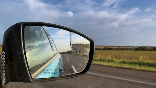 Side mirror of a car close-up. Car mirror with reflection of the road close-up. Traveling by car. Summer travel, reflection in the rear view mirror.