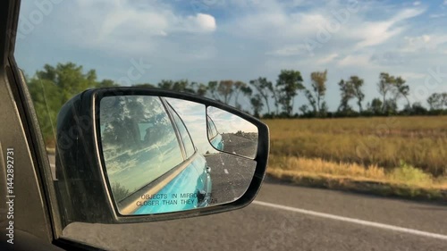 Side mirror of a car close-up. Car mirror with reflection of the road close-up. Traveling by car. Summer travel, reflection in the rear view mirror.