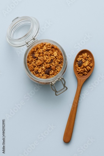 Granola in a Glass Jar With a Wooden Spoon on a Light Blue Background