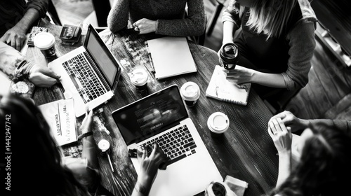 A diverse group of four people engaged in a meeting around a wooden table.