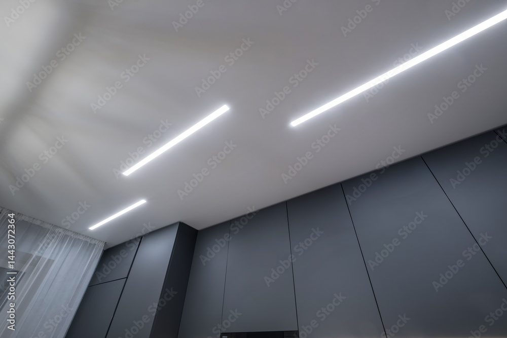 suspended ceiling with halogen spots lamps in form of squares and rectangles and drywall construction in empty room in apartment or house. Stretch ceiling white and complex shape.