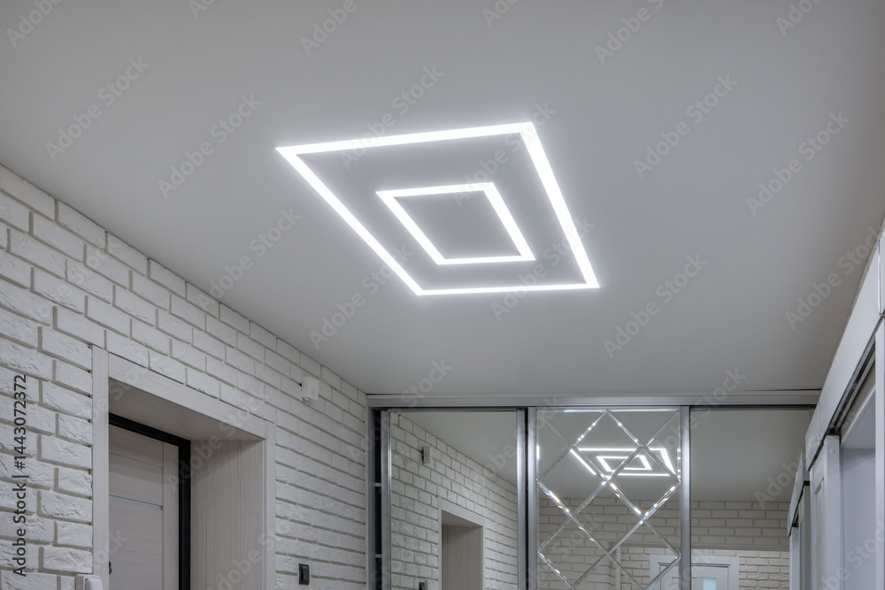 suspended ceiling with halogen spots lamps in form of squares and rectangles and drywall construction in empty room in apartment or house. Stretch ceiling white and complex shape.