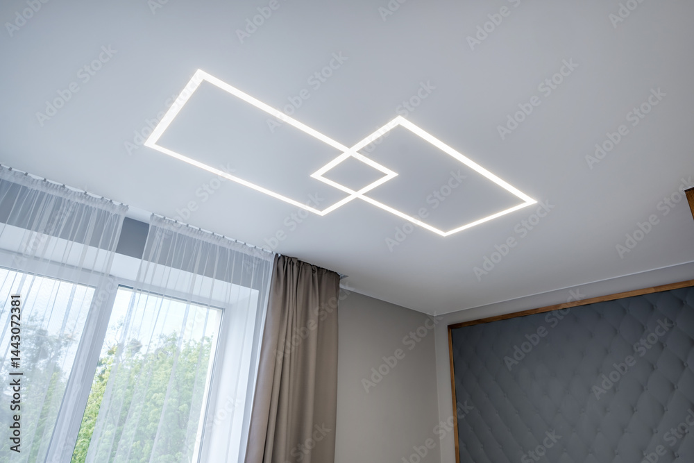 suspended ceiling with halogen spots lamps in form of squares and rectangles and drywall construction in empty room in apartment or house. Stretch ceiling white and complex shape.
